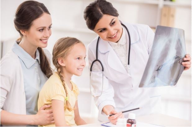 doctora viendo radiografia con niña y mama