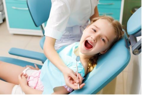 niña abriendo la boca con dentista